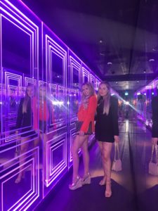 Women posing in a mirror room with purple neon lights during a night out at Mnky House