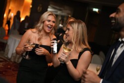Two women enjoying wine and conversation at an indoor social event in Barbican